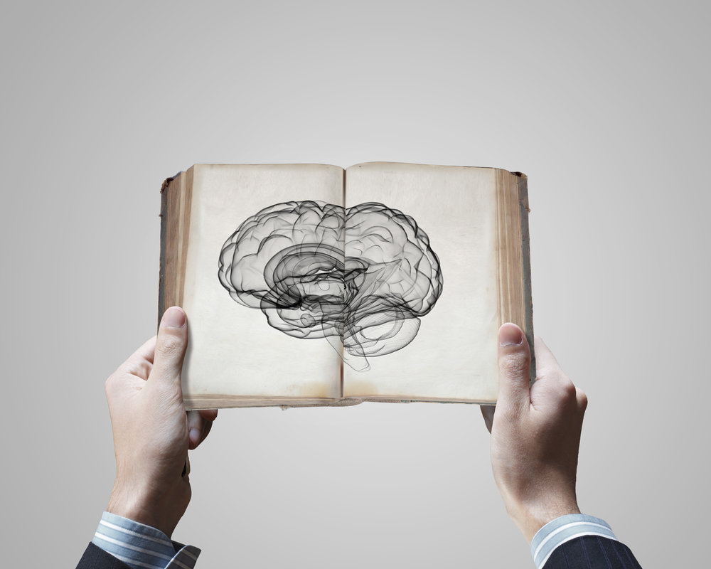 Close up of male hands holding opened book with brain picture