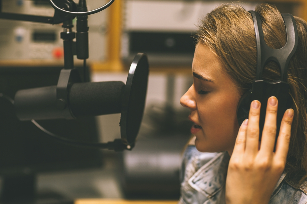 Focused pretty singer recording a song in studio at college